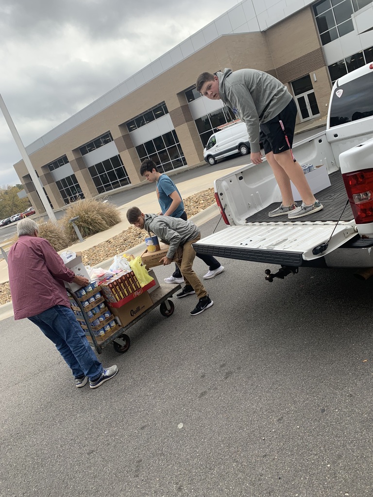 NHS members stack cans of food in a truck